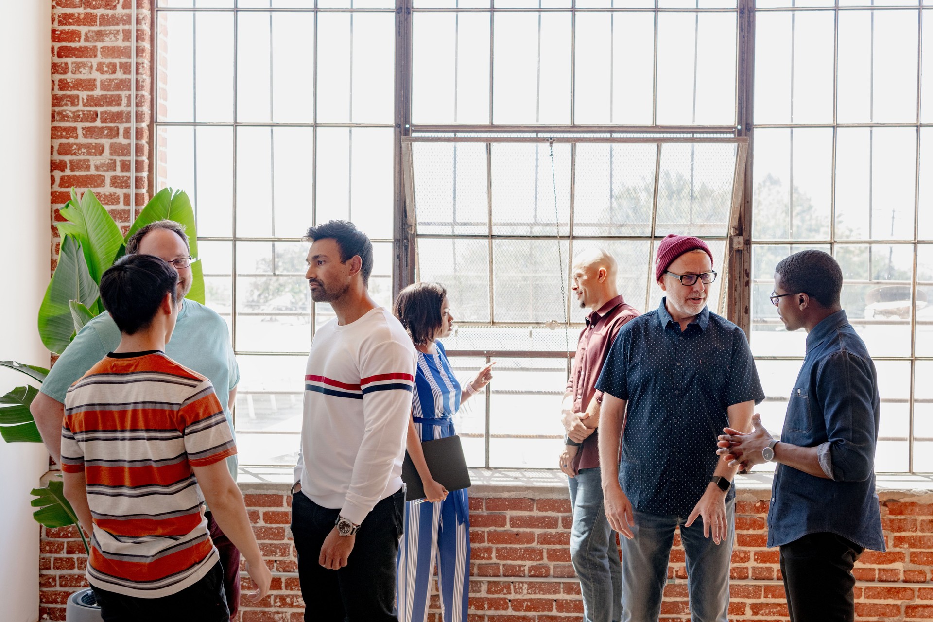 Diverse group in casual attire socializing in a modern loft for new community and connection.